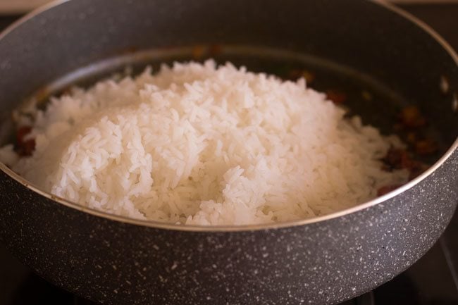 adding cooked rice to spice mixture in the pan