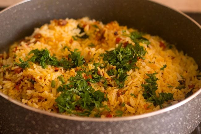 adding chopped coriander leaves to masala rice in pan