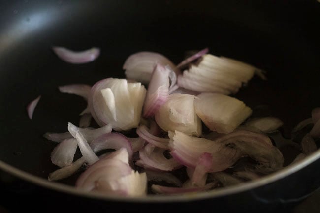 adding sliced onions to hot oil in pan