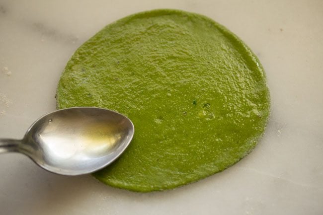 ghee on the top of the rolled palak paratha dough