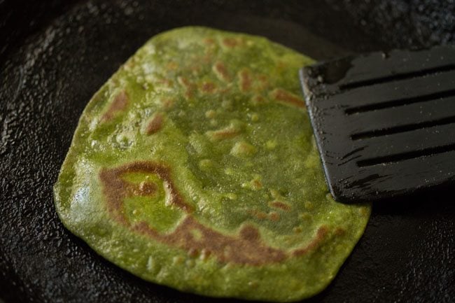 Pressing the paratha edges with a spatula