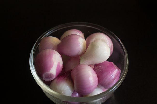peeled small red onions in a glass bowl to make pickled onions recipe