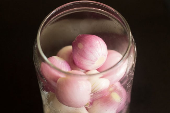 placing rinsed small red onions in a glass jar 