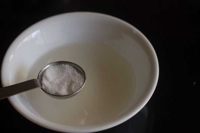 adding salt to vinegar-water mixture in bowl