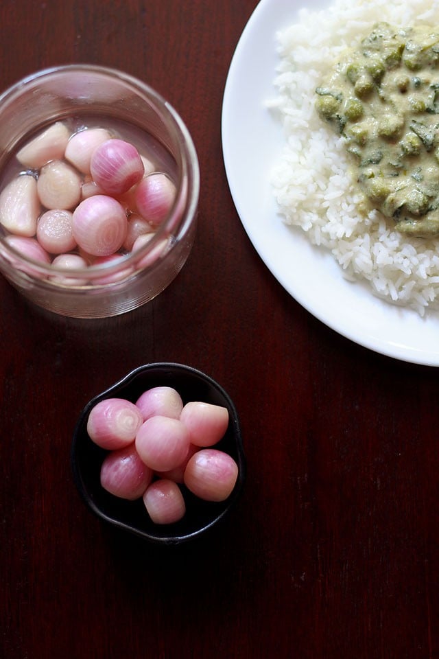 pickled onions served in a bowl with rice and curry in a plate and jar of pickled onions on the side 