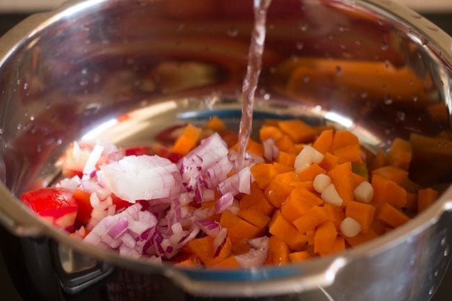 adding chopped vegetables and water in a pressure cooker 