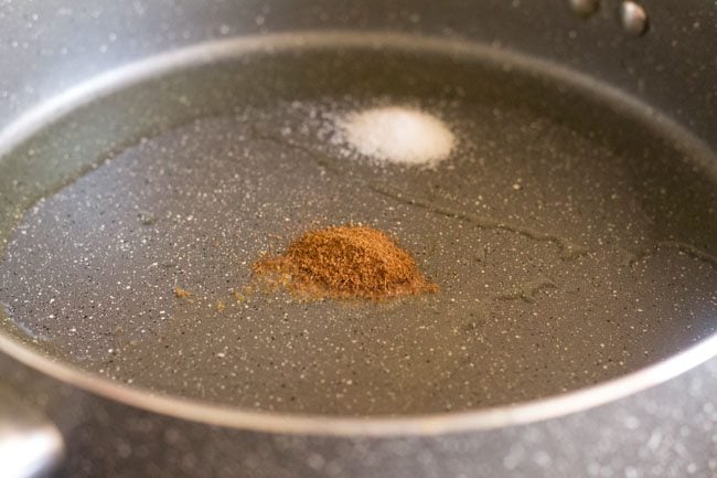 adding cumin powder and salt to hot olive oil in pan