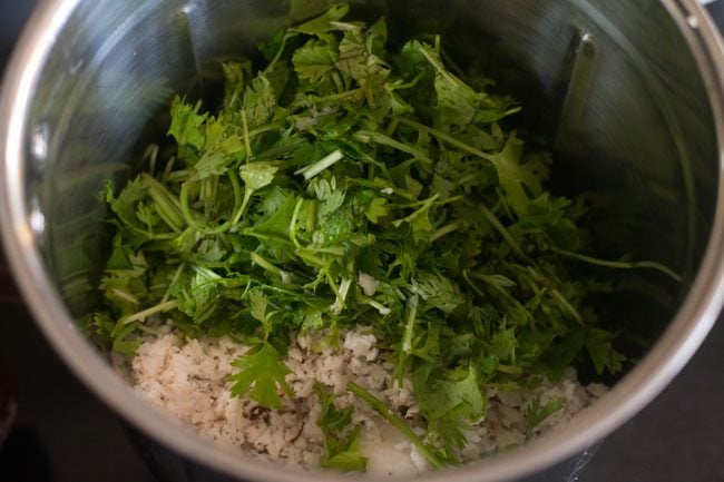 coriander leaves and grated coconut added to blender jar for making coriander coconut chutney. 