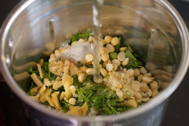 adding water in blender jar for making coriander coconut chutney. 