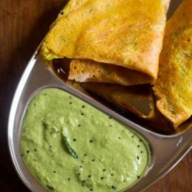 green coconut chutney served in a plate with a dosa.