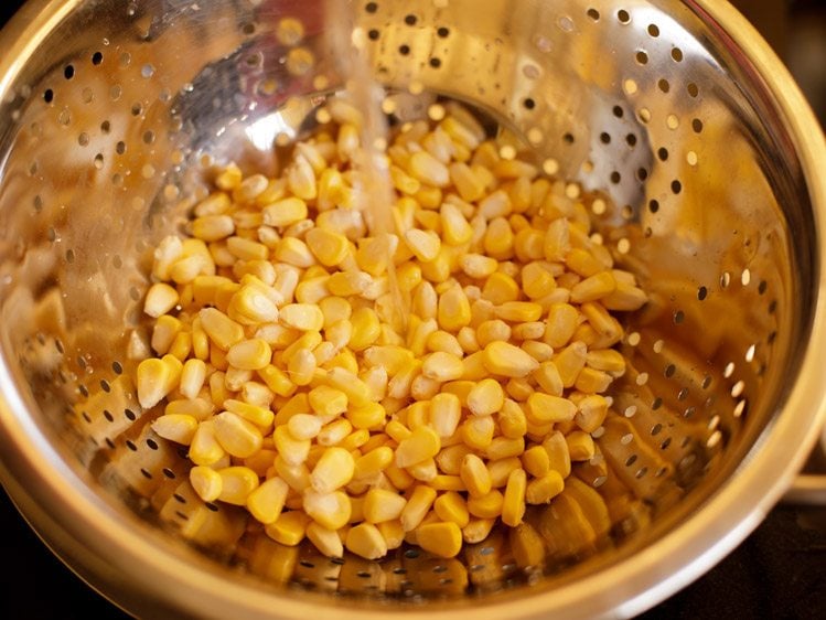 rinsing corner kernels in a steel colander for corn chaat recipe. 