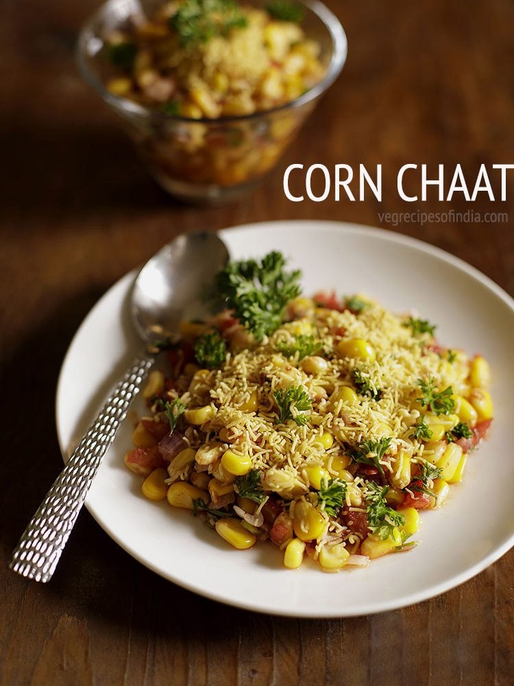 corn chaat served on a white plate with a spoon in it with text layovers.