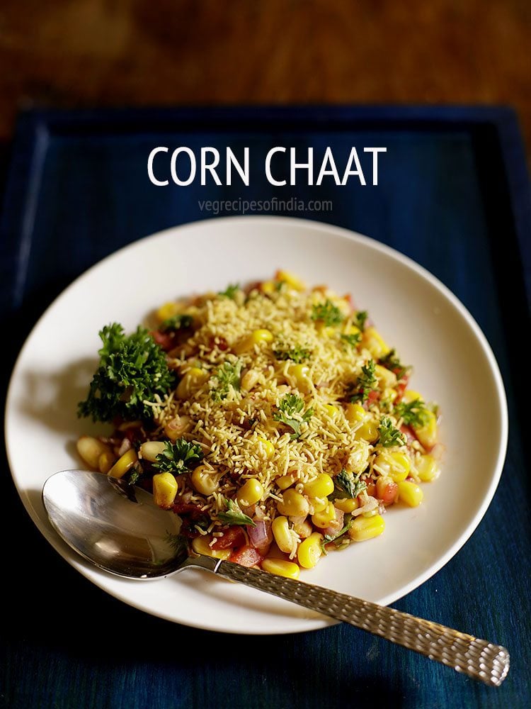 corn chaat served on a white plate with a spoon. 