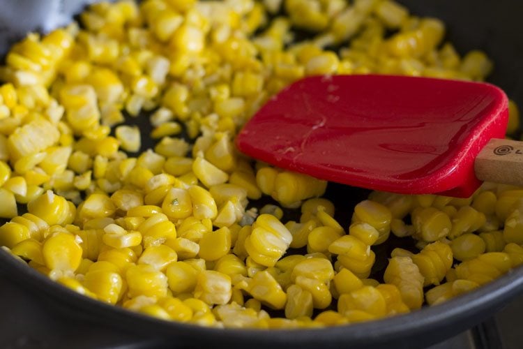 stirred oil, garlic and corn kernels in a pan