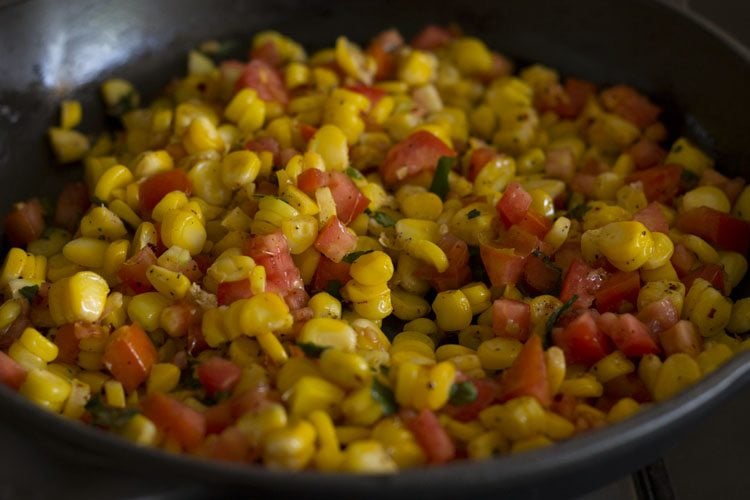 seasoned corn with tomatoes and basil leaves cooled down