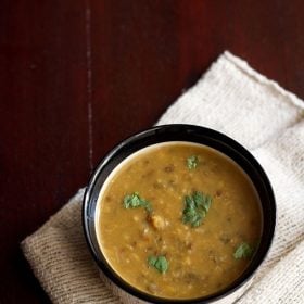 maa chole ki dal garnished with coriander leaves and served in a black bowl.