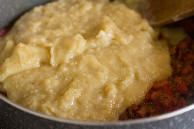 lightly mashed red lentils on top of onion-tomato masala in pan.