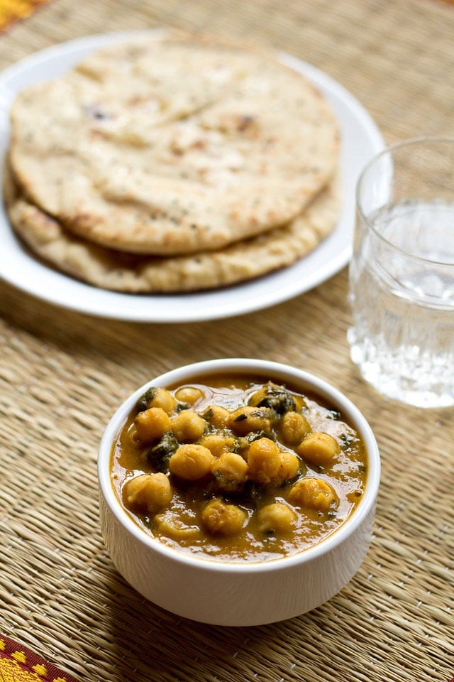 methi chole served in a bowl with naan and a glass of water.