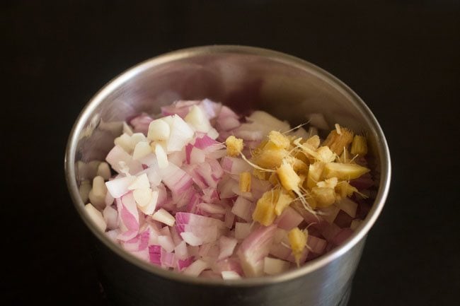 adding chopped onion, chopped ginger and chopped garlic to blender jar for onion paste