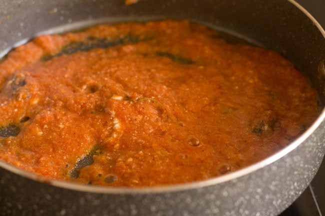 stirring tomato paste and curd in pan