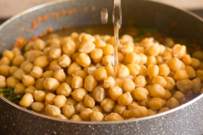 adding cooked chole and water in pan