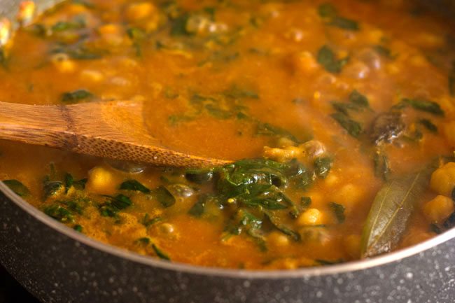 mashing a few chole to thicken gravy in pan