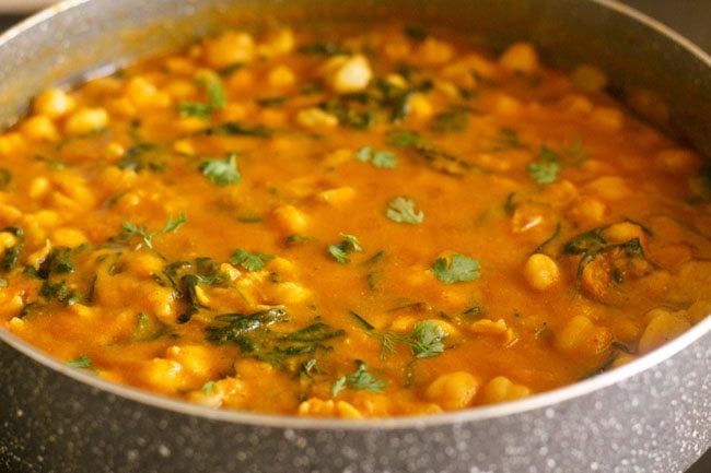 garnishing methi chole in pan with coriander leaves 