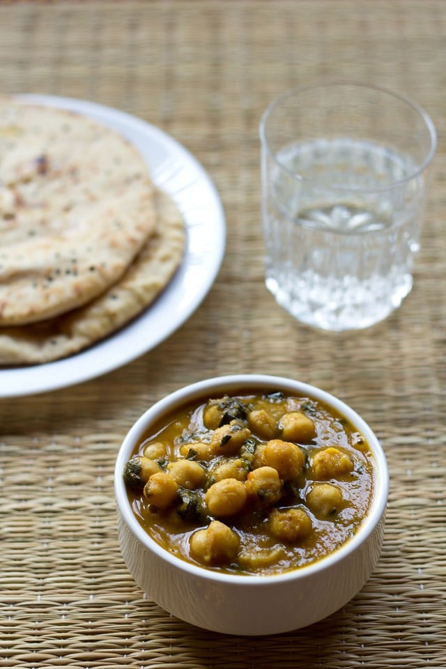 methi chole served in a bowl with naan and a glass of water 