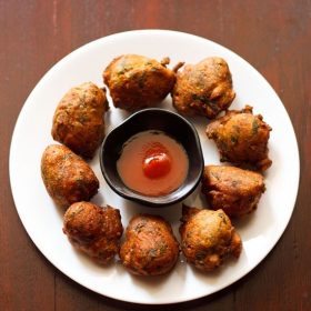 methi na gota served on a white plate with a bowl of sauce kept in the center.