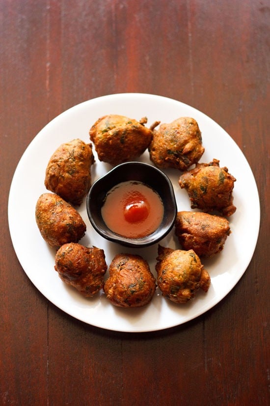 methi na gota served on a white plate with a bowl of sauce kept in the center.