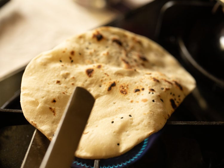 roasting naan edges on direct flame using tongs