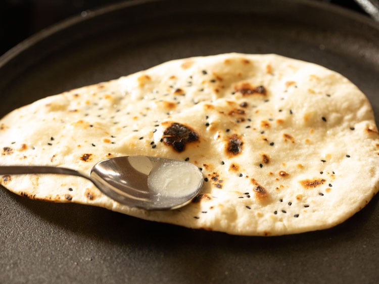 applying butter on cooked naan bread