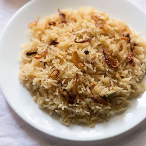 parsi brown rice served on a white plate.