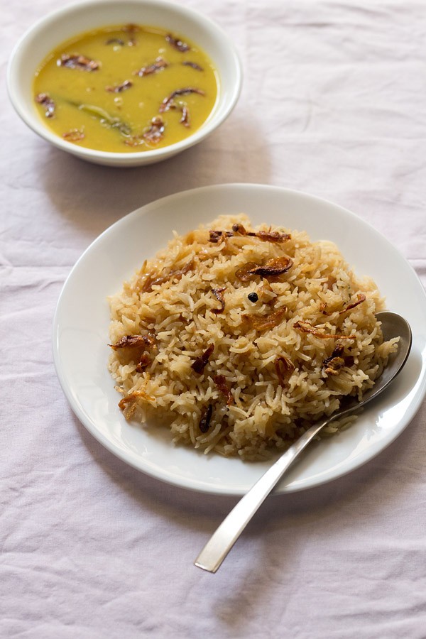 parsi brown rice served on a white plate with a spoon and parsi dal kept in a bowl on the top left side. 