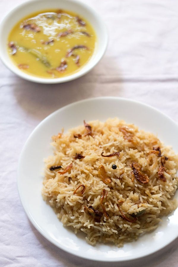 parsi brown rice served on a white plate with dal in a bowl kept on the top side and text layovers.