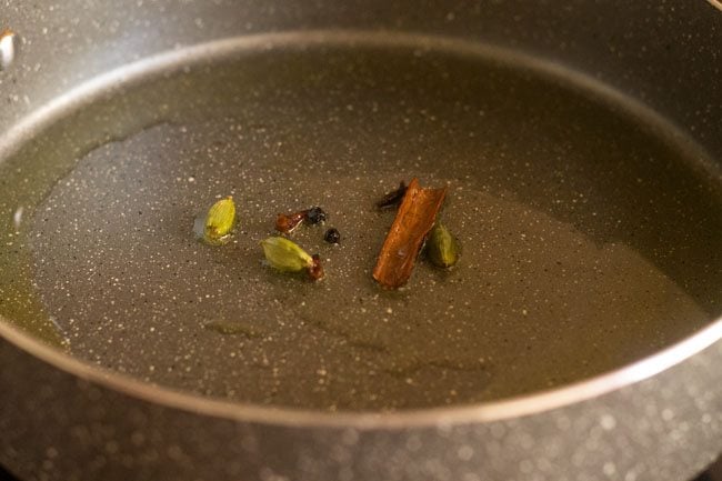 cinnamon, green cardamoms, cloves and whole black peppercorns added to the hot ghee in the pot. 