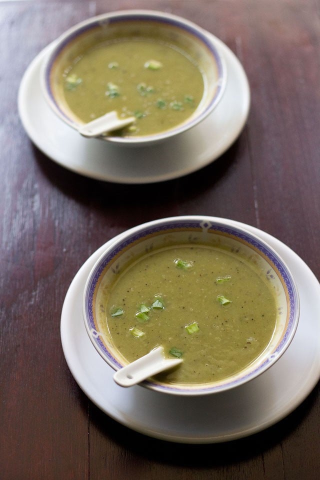 spring onion soup served in soup bowls on a white plate with soup spoons inside the soup. 