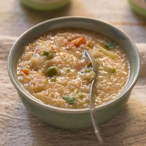 dalia khichdi garnished with coriander leaves and served in a ceramic bowl.