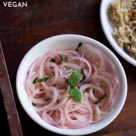 onion salad garnished with mint leaves and served in a white bowl with text layover.