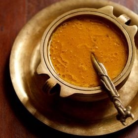 carrot payasam served in a brass bowl placed on a brass plate with a brass spoon placed in the kheer.