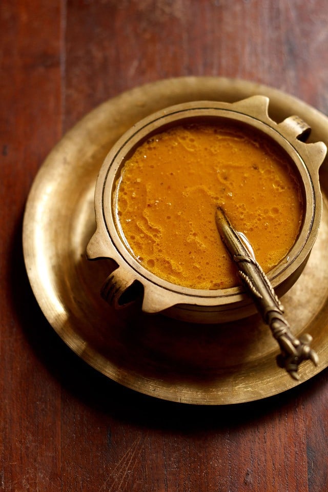 carrot payasam served in a brass bowl placed on a brass plate with a brass spoon placed in the kheer.