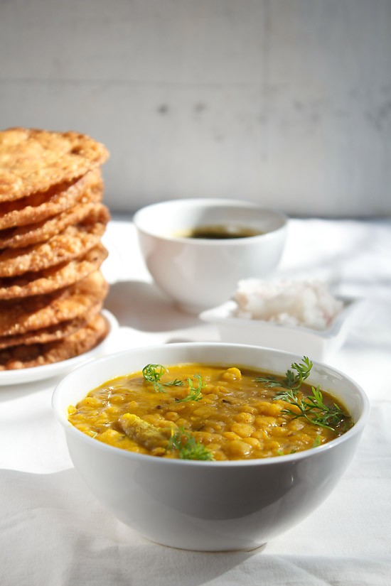 dal pakwan served in a bowl and plate with a small bowl of chutney and chopped onions kept in the background. 