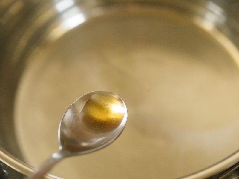 sesame oil in a steel spoon above a pan with water