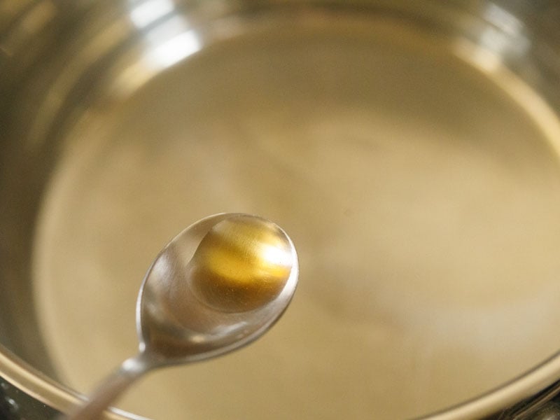 óleo de gergelim em uma colher de aço cima de uma panela com água