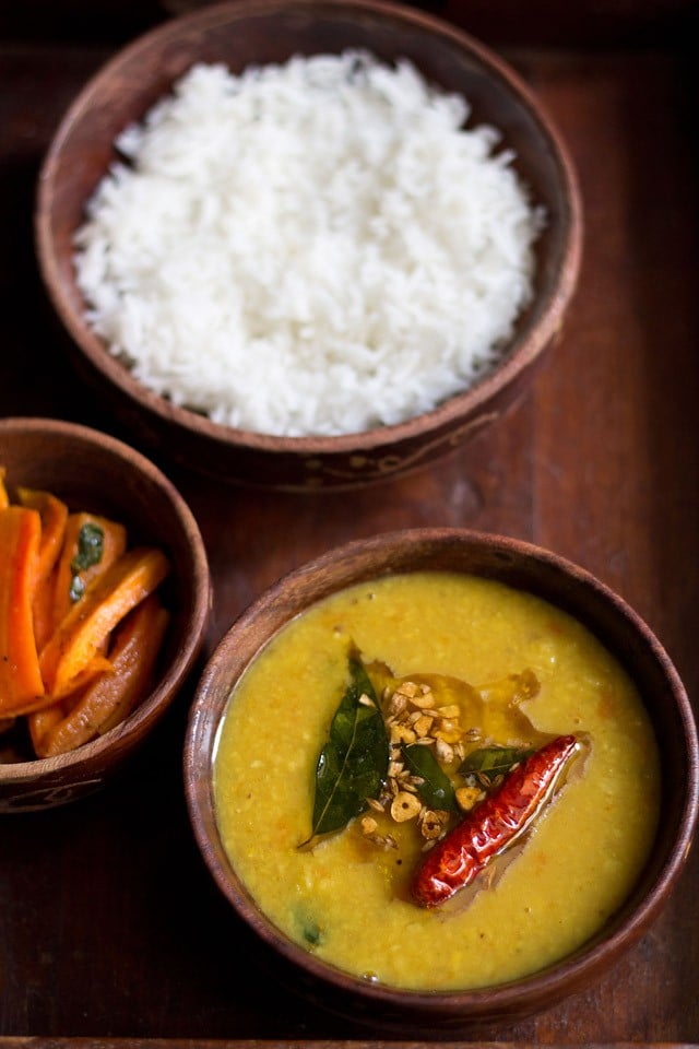 khatti dal served in a bowl with steamed rice, salad