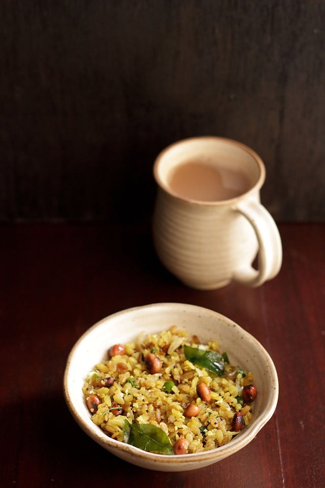 kanda poha servita in una ciotola di ceramica con un lato di chai indiano in una tazza di ceramica