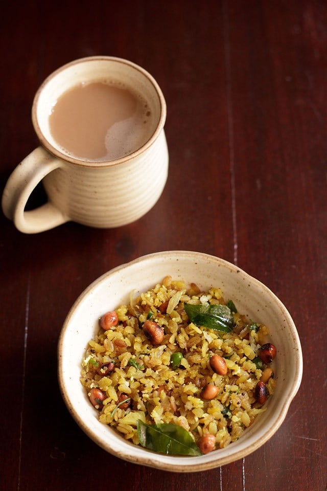 Kanda Poha serviert in einer Keramikschüssel mit einer Seite indischen Chai in einem Keramikbecher