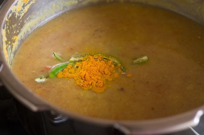 adding green chilies and turmeric powder to dal