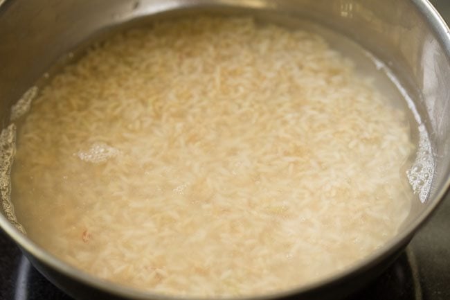 soaking rice in water in a steel bowl to make chitranna or lemon rice