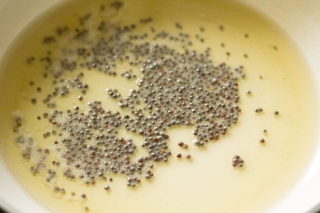 frying mustard seeds in oil in a pan
